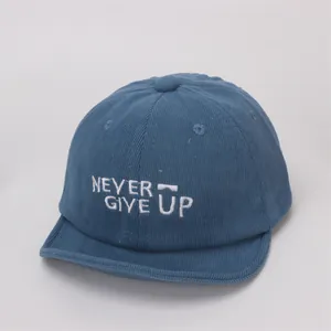 Detalle de pana azul de la gorra para bebé con bordado de letras 'NEVER GIVE UP'