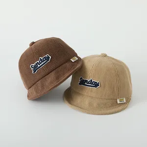 Texture détaillée du velours côtelé des casquettes bébé marron et beige avec broderie