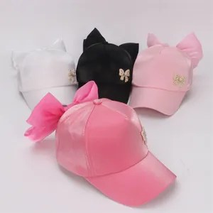 Detailed view of girls baseball caps with large silk bows and rhinestone butterfly accents