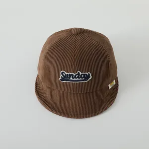 Gros plan sur la texture en velours côtelé marron du bonnet bébé avec broderie Sunday