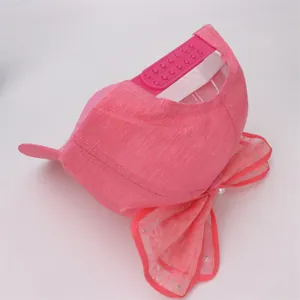 Detalle de gorra rosa con lazo de encaje, perlas y correa trasera ajustable para niñas