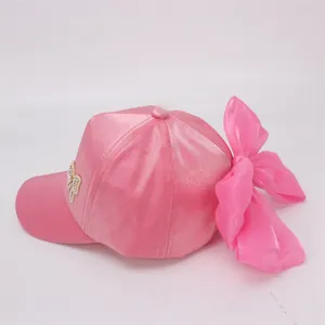 Detailed back view of pink satin girl's baseball cap featuring a large sheer bow and pearls