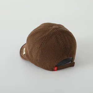Vue détaillée casquette bébé en velours côtelé marron avec sangle réglable et étiquette rouge