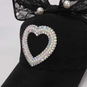 Detalle de gorra negra con lazo grande de encaje, perlas y corazón de diamantes de imitación