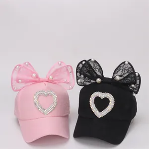 Detalle de gorras de béisbol para niñas con lazos de encaje, perlas y corazón de diamantes