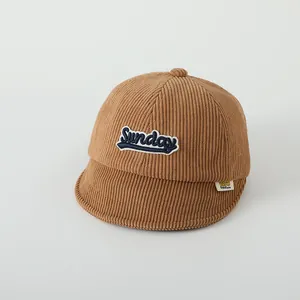 Détail de la broderie Sunday sur la casquette bébé en velours côtelé caramel
