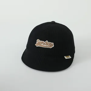 Détail de la casquette bébé en velours côtelé noir avec broderie Sunday et étiquette