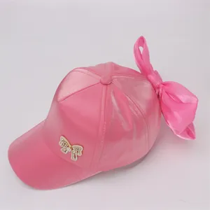 Detail of pink satin baseball cap featuring a large bow and pearl butterfly ornament