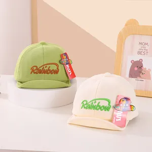 Close-up of soft-brim baby baseball caps in green and beige with Rainbow embroidery