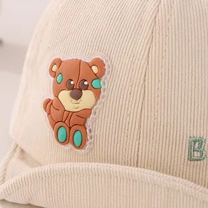 Close-up of beige corduroy baby hat with cute 3D bear patch and green letter embroidery
