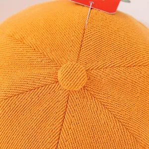 Macro detail of orange knit baby baseball cap featuring reinforced seams and top button