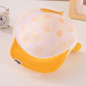 Detailed view of yellow baby baseball cap featuring cotton lining with orange polka dots
