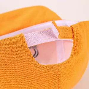 Detail of adjustable velcro strap on orange cotton baseball cap for toddlers
