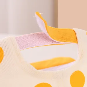 Detail of adjustable velcro strap and yellow polka dot corduroy fabric on baby hat
