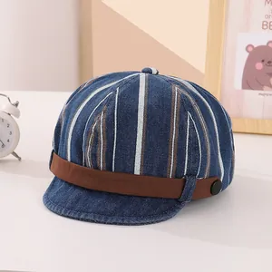Détail de la casquette rayée en denim pour bébé avec bord souple et bande en cuir brun
