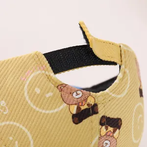 Detail of adjustable velcro strap on yellow corduroy baby cap with bear and smile prints