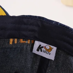 Détail intérieur d'une casquette en denim avec étiquette tissée KUKUJI et broderie