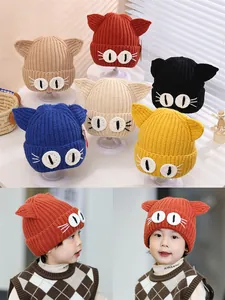 Close-up of thick knitted baby hats featuring cute cat ears and large eye embroidery
