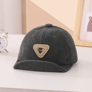 Detailed texture of dark grey corduroy baby cap with leather C-letter patch detail