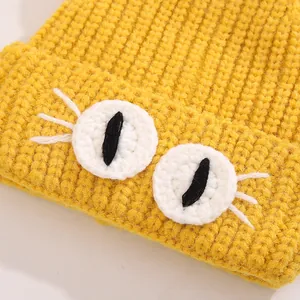 Detailed macro shot of yellow knitted hat featuring cute cartoon eyes and chunky weave