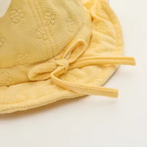 Dettaglio cappello neonato giallo in tessuto waffle con fiocco e orsetti