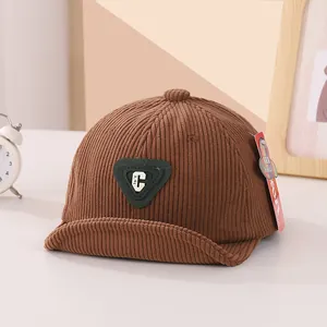 Detail of baby brown corduroy baseball cap with green C letter patch and soft brim