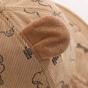 Close-up of khaki corduroy bucket hat showing bear ears and hand-drawn cartoon print