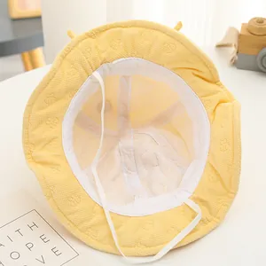 Dettaglio cappello neonato giallo in maglia a nido d'ape con fodera orso e cordino