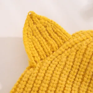 Close-up of bright yellow knit baby hat featuring 3D cat ear detail and ribbed texture