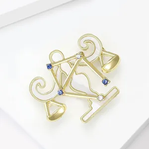 Élégante broche Balance en or avec émail blanc et strass bleus brillants pour vêtements