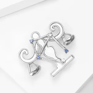 Détail macro d'une broche Balance en argent ornée de strass bleus et blancs
