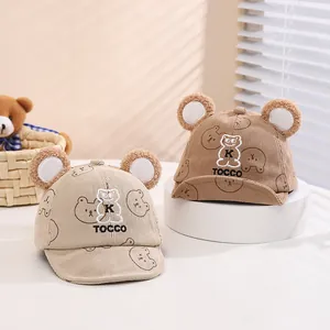 Dettaglio di cappellini per neonati in velluto beige e kaki con orecchie d'orso e ricami