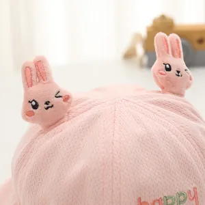 Dettaglio cappello neonato in cotone rosa con ricamo happy e decorazione orecchie di coniglio