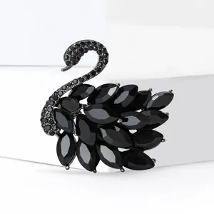 Elegante broche de cisne negro con cristales sobre un soporte geométrico blanco