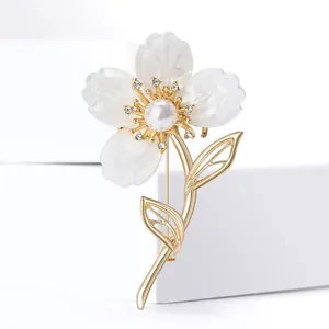 Macro de la broche fleur à 4 pétales en résine avec perle centrale et feuilles d'or
