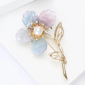 Détail d'une élégante broche fleur en résine violette avec feuilles dorées et perles