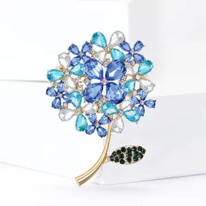 Elegant hydrangea flower brooch with blue crystals on golden base over white background