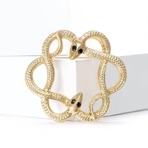 Broche serpent double dorée élégante avec yeux en zircon sur socle blanc minimaliste