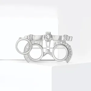 Polished silver optometrist trial frame brooch with white crystal accents on white block