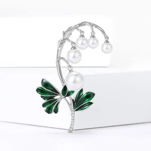 Elegante lelie-van-dalen broche met groene emaille bladeren en witte parels op een witte voet