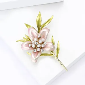 Detailed view of enamel flower brooch with pink petals, pearls and crystals on white stand