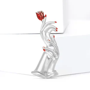 Artistic enamel rose brooch featuring silver hands holding a red rose flower