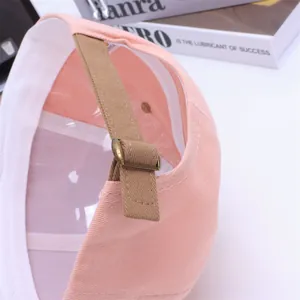 Detail of pink cotton baseball cap with adjustable brown strap and bronze metal buckle