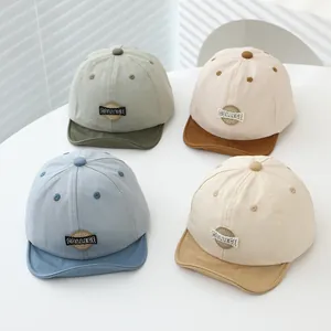 Flat lay set of four soft-brim baby baseball caps in neutral earth-tone color palettes