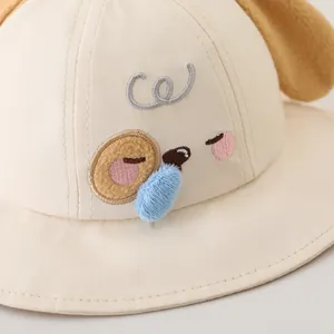 Beige cotton kids bucket hat featuring cartoon dog embroidery and 3D plush blue detail