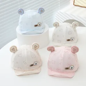 Detail view of cotton baby caps with bear ears and heart embroidery in four pastel colors