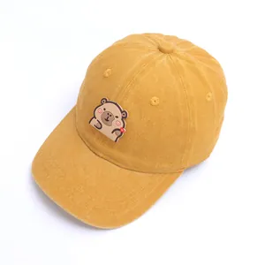 Primer plano de la textura de pana amarilla y el parche de carpincho en la gorra infantil