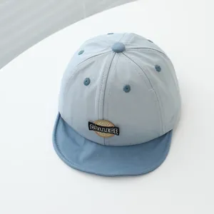 Detail of baby baseball cap with American college style embroidery on light blue fabric
