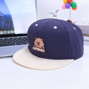 Kids navy and beige capybara baseball cap with metal sprout accent on a white desk