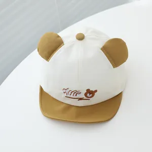 Détail d'une casquette bébé avec oreilles d'ours 3D et broderie de croissant